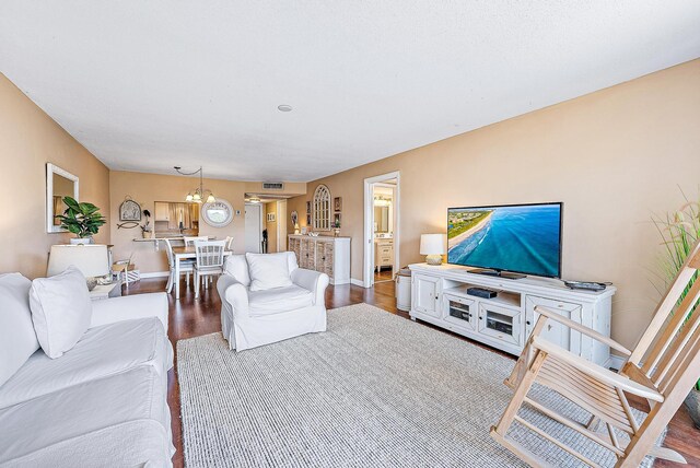 living area with baseboards, wood finished floors, and a chandelier