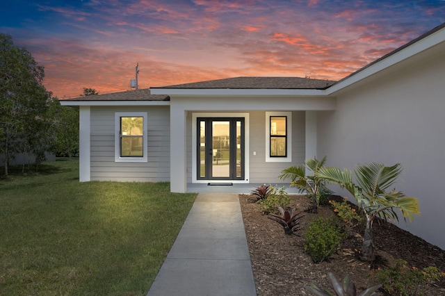 4665 SW Keats St, Port Saint Lucie, FL 34953 - exterior entry at dusk with a lawn, roof with shingles, and covered porch