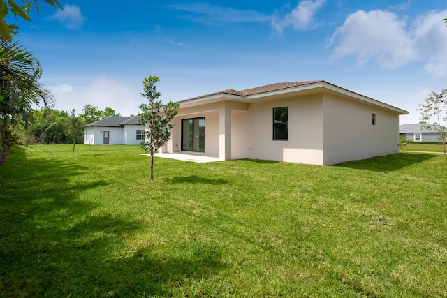 4665 SW Keats St, Port Saint Lucie, FL 34953 - back of property featuring stucco siding, a lawn, and a patio area