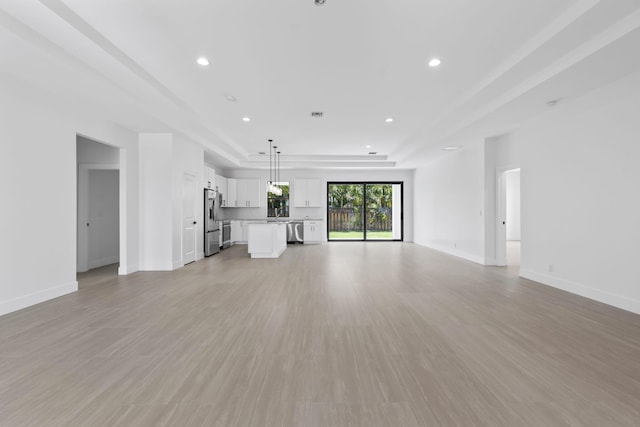 4665 SW Keats St, Port Saint Lucie, FL 34953 - unfurnished living room featuring recessed lighting, baseboards, light wood-style floors, and a tray ceiling