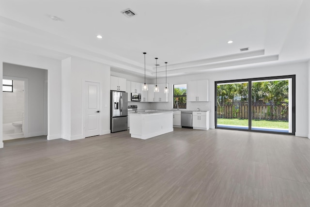 4665 SW Keats St, Port Saint Lucie, FL 34953 - unfurnished living room featuring a tray ceiling, a sink, wood finished floors, recessed lighting, and baseboards