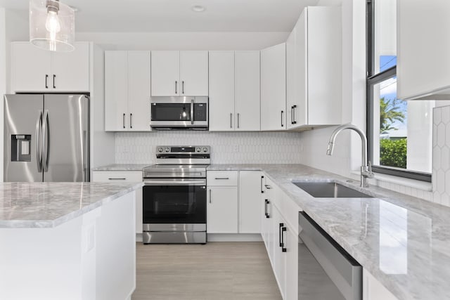4665 SW Keats St, Port Saint Lucie, FL 34953 - kitchen with appliances with stainless steel finishes, a sink, light stone counters, and decorative backsplash