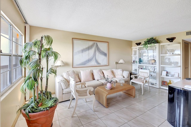 living area with visible vents, a textured ceiling, and light tile patterned floors