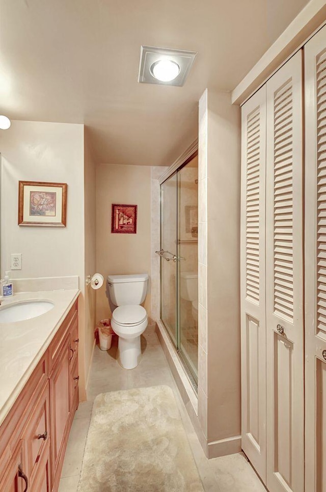 full bath featuring vanity, toilet, tile patterned floors, a stall shower, and a closet
