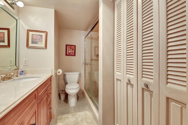 bathroom with tile patterned flooring, vanity, toilet, a shower stall, and a closet