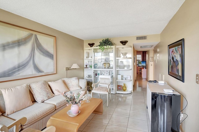 living area featuring light tile patterned flooring, a textured ceiling, and visible vents