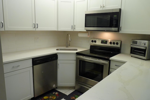 kitchen with a sink, backsplash, stainless steel appliances, and a toaster