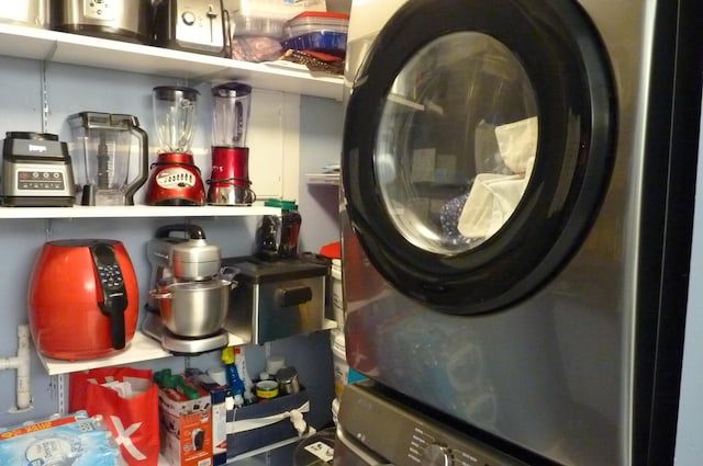 clothes washing area with stacked washing maching and dryer and laundry area