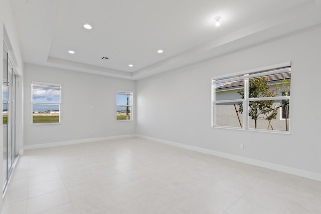 spare room featuring recessed lighting, a raised ceiling, baseboards, and visible vents