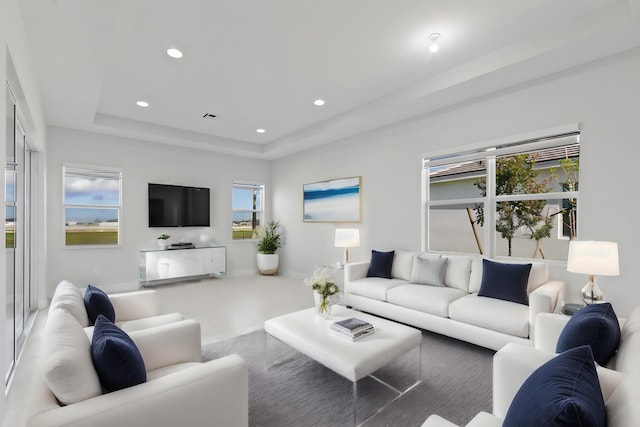 living room featuring recessed lighting, a raised ceiling, baseboards, and visible vents