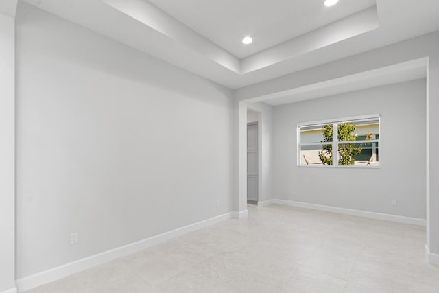 spare room with recessed lighting, baseboards, and a tray ceiling