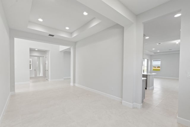 spare room featuring visible vents, recessed lighting, a raised ceiling, and baseboards