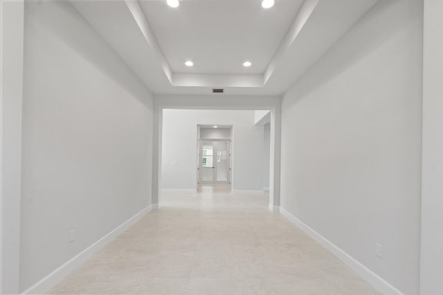 corridor with a raised ceiling, baseboards, recessed lighting, and visible vents