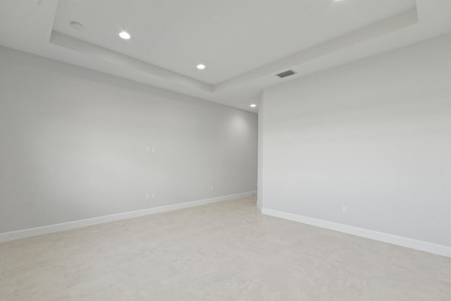spare room featuring recessed lighting, a raised ceiling, baseboards, and visible vents