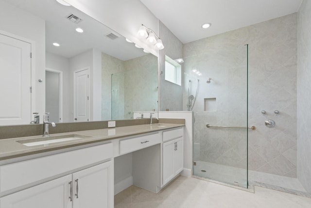 bathroom featuring a sink, a tile shower, double vanity, and visible vents