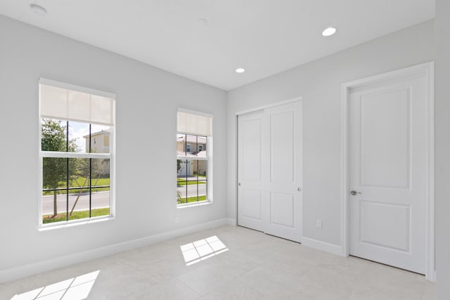 unfurnished bedroom with light tile patterned floors, baseboards, a closet, and recessed lighting