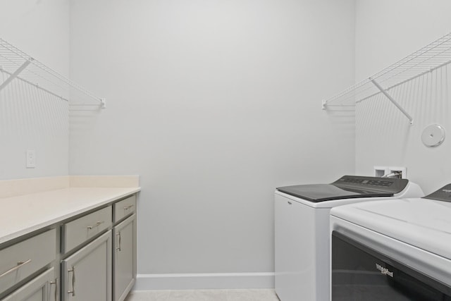 laundry area with baseboards, cabinet space, and washer and clothes dryer
