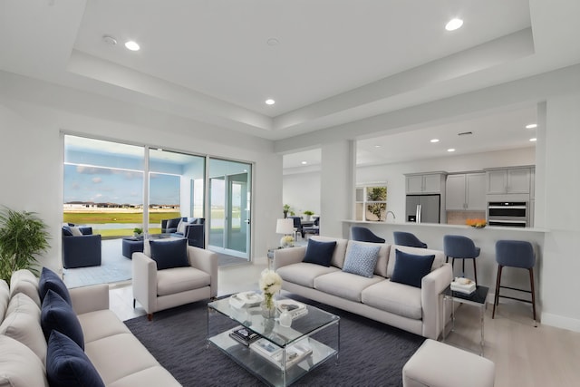 living room with recessed lighting, baseboards, and a tray ceiling