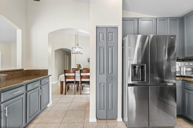 kitchen featuring arched walkways, light tile patterned floors, gray cabinetry, and stainless steel fridge with ice dispenser