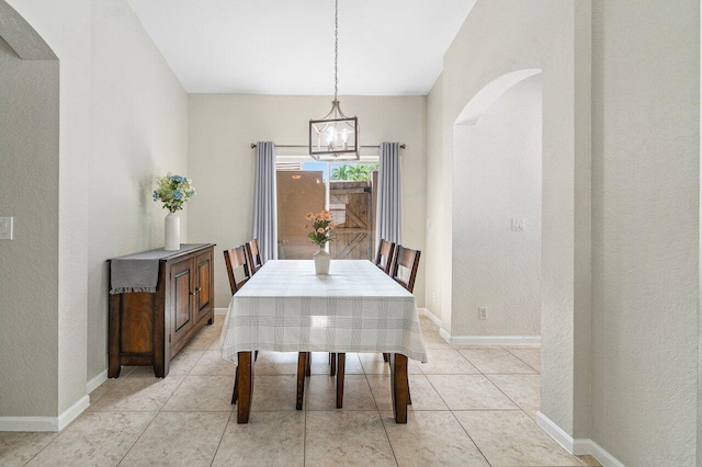 dining space featuring baseboards, arched walkways, light tile patterned floors, and a notable chandelier