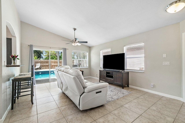 living area featuring light tile patterned flooring, ceiling fan, baseboards, and lofted ceiling