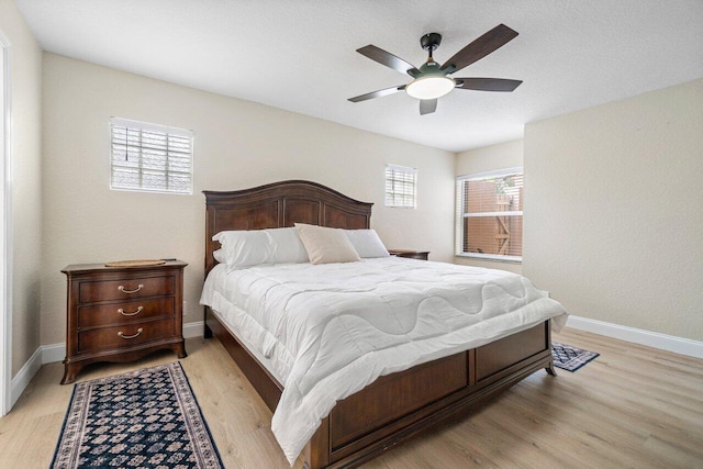 bedroom featuring light wood-style floors, a ceiling fan, and baseboards