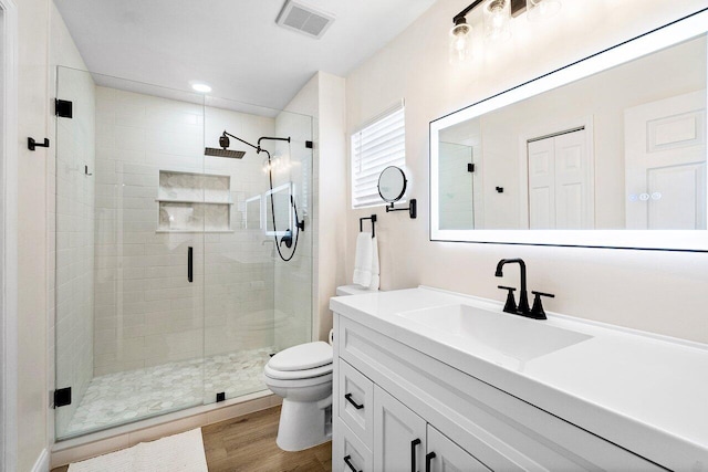 full bathroom featuring vanity, toilet, wood finished floors, visible vents, and a stall shower