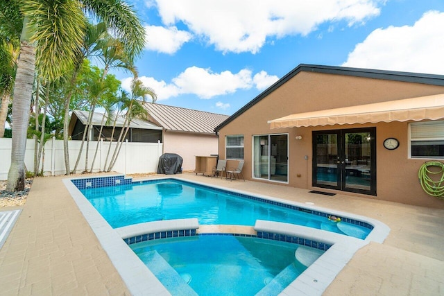 view of swimming pool with a patio, fence, french doors, and a pool with connected hot tub