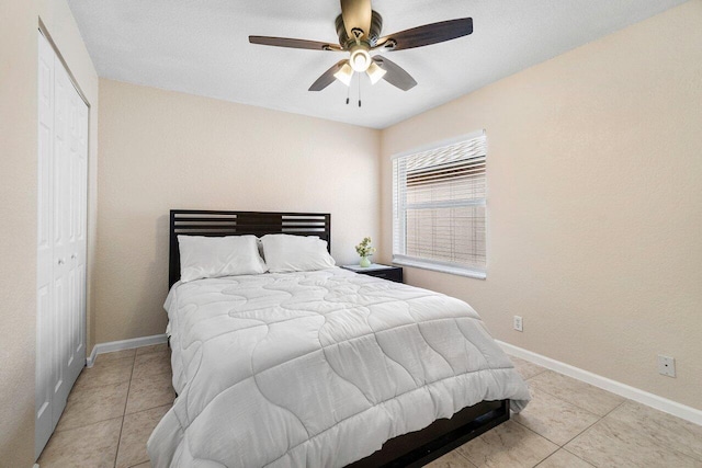 bedroom with baseboards, ceiling fan, a closet, and light tile patterned flooring