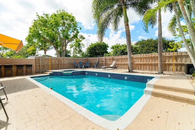 view of pool with a fenced backyard, outdoor dry bar, a patio, and a pool with connected hot tub