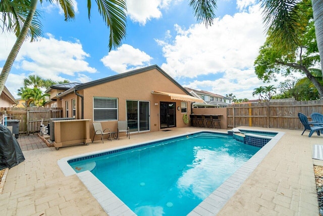 view of pool featuring a patio, a pool with connected hot tub, a fenced backyard, and outdoor dry bar