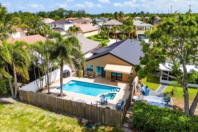 view of swimming pool with a fenced backyard, a pool with connected hot tub, a patio area, and a residential view