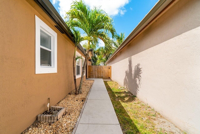 view of side of home with stucco siding and fence