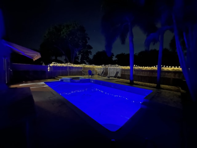 pool at twilight featuring a fenced in pool, a fenced backyard, a hot tub, and a patio