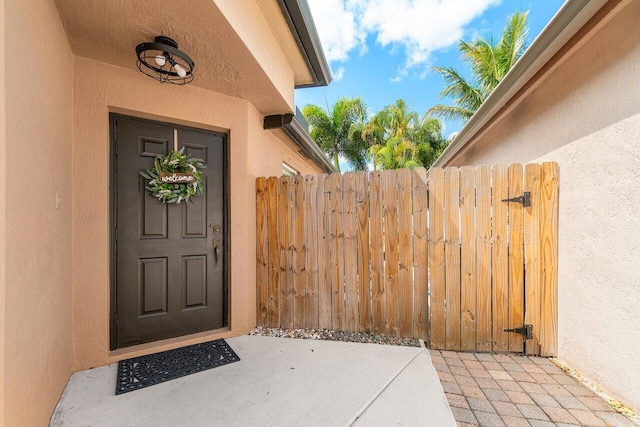 entrance to property with fence and stucco siding