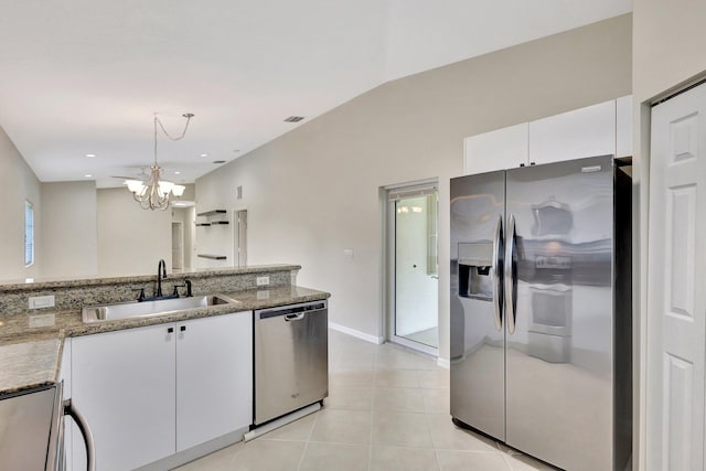 kitchen with an inviting chandelier, light stone counters, a sink, stainless steel appliances, and white cabinetry
