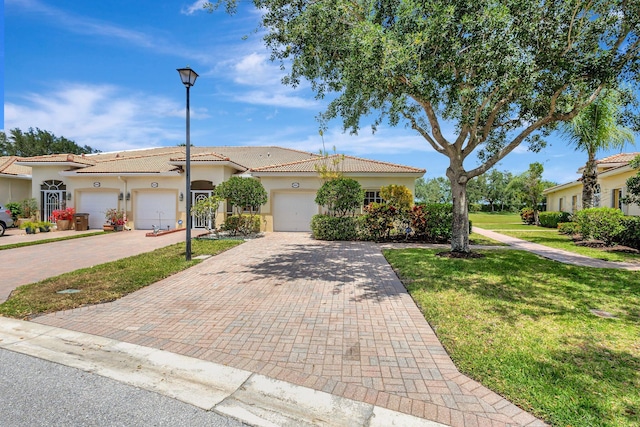 view of front of home with a tile roof, a front yard, decorative driveway, an attached garage, and stucco siding
