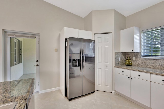 kitchen with decorative backsplash, stainless steel refrigerator with ice dispenser, white cabinetry, light stone counters, and light tile patterned flooring