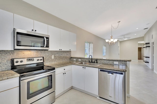 kitchen with a sink, a peninsula, light tile patterned floors, and stainless steel appliances