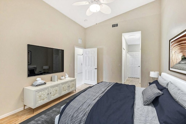 bedroom with visible vents, light wood-style floors, baseboards, ceiling fan, and high vaulted ceiling
