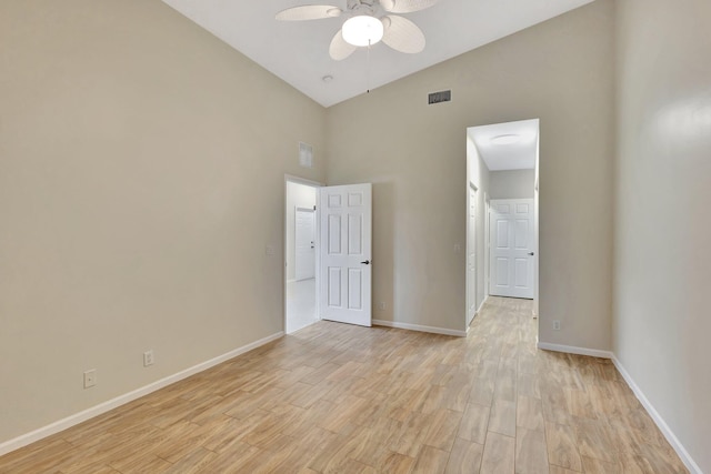 spare room with visible vents, light wood-style floors, baseboards, high vaulted ceiling, and a ceiling fan