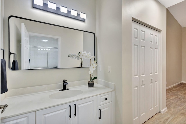 full bath with an enclosed shower, baseboards, wood finished floors, and vanity