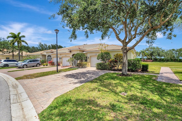 view of front of house featuring an attached garage, a front lawn, stucco siding, and decorative driveway