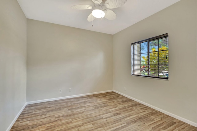 spare room featuring baseboards, ceiling fan, and light wood finished floors