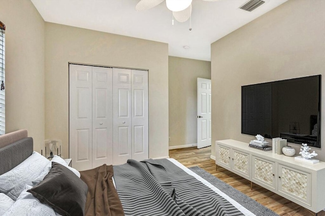 bedroom with visible vents, a closet, wood finished floors, baseboards, and ceiling fan