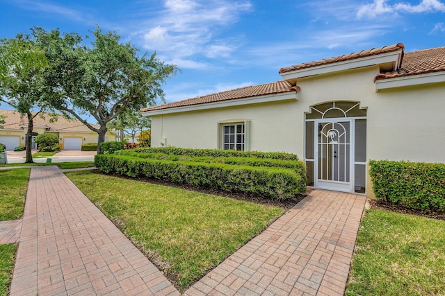 doorway to property featuring a lawn, a tiled roof, and stucco siding