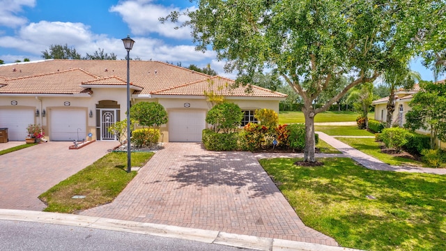 view of front of property with decorative driveway, a front lawn, a tile roof, and stucco siding