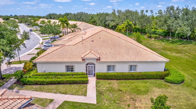 exterior space featuring a front lawn, stucco siding, and a tiled roof