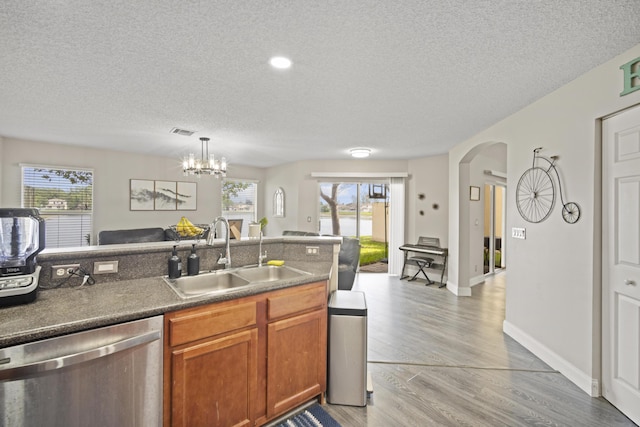 kitchen with a sink, a textured ceiling, dishwasher, and open floor plan