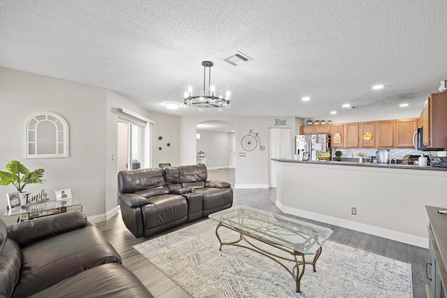 living room with visible vents, arched walkways, wood finished floors, baseboards, and recessed lighting